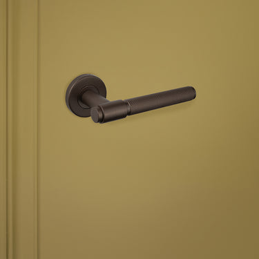 Stijlvolle bronzen deurgreep met reliëfstructuur gemonteerd op binnendeur, linkeraanzicht