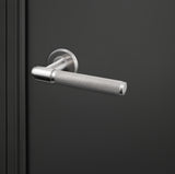 Moderne Lavuzo Cosenza deurklink RVS met gekartelde greep op zwarte deur, rechteraanzicht