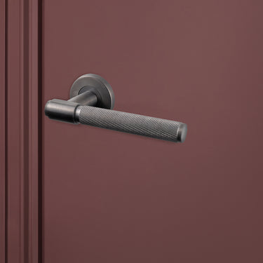 Luxe Cosenza binnendeurbeslag Gun Metal PVD Knurled op donkerrode deur, rechteraanzicht
