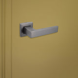 Gun Metal deurgreep Imperio op vierkante rozet van Lavuzo op groene deur, linkeraanzicht