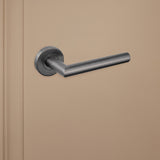 Strakke Gun Metal Mantua binnendeurklink van Lavuzo op beige achtergrond, linkeraanzicht