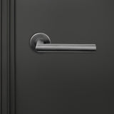 Lavuzo Mantua deurklink Gun Metal PVD op rond rozet strak gemonteerd op donkere binnendeur, vooraanzicht